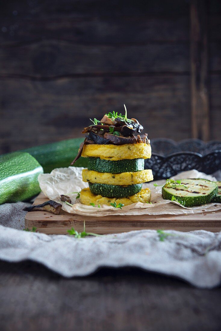 A vegan tower made of polenta rounds and slices of courgette with porcini mushrooms