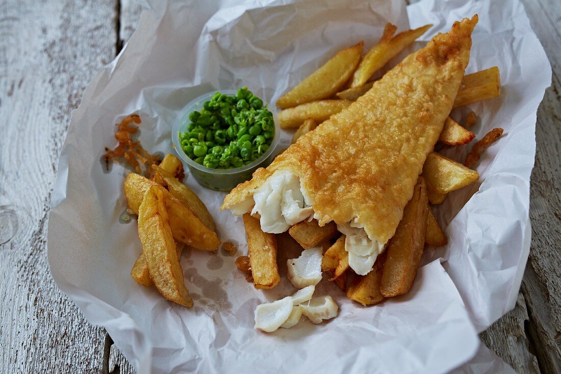 Fish and chips with mushy peas on paper
