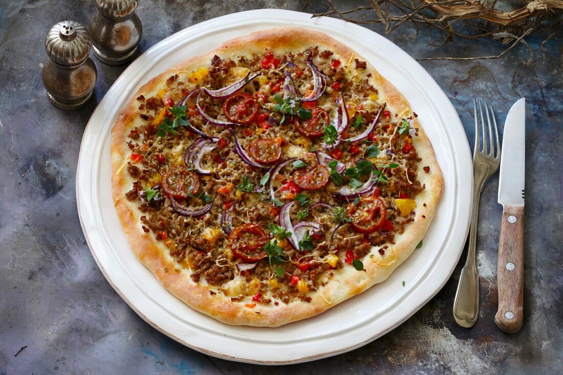 Pizza with minced meat, onions and tomatoes