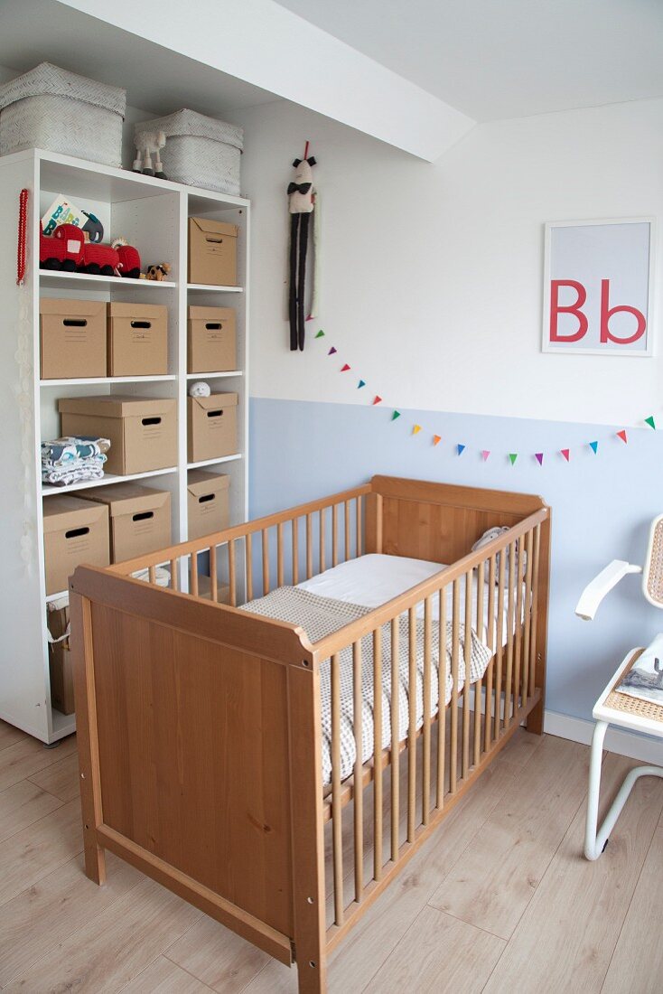 Cot against two-tone wall and boxes on shelves