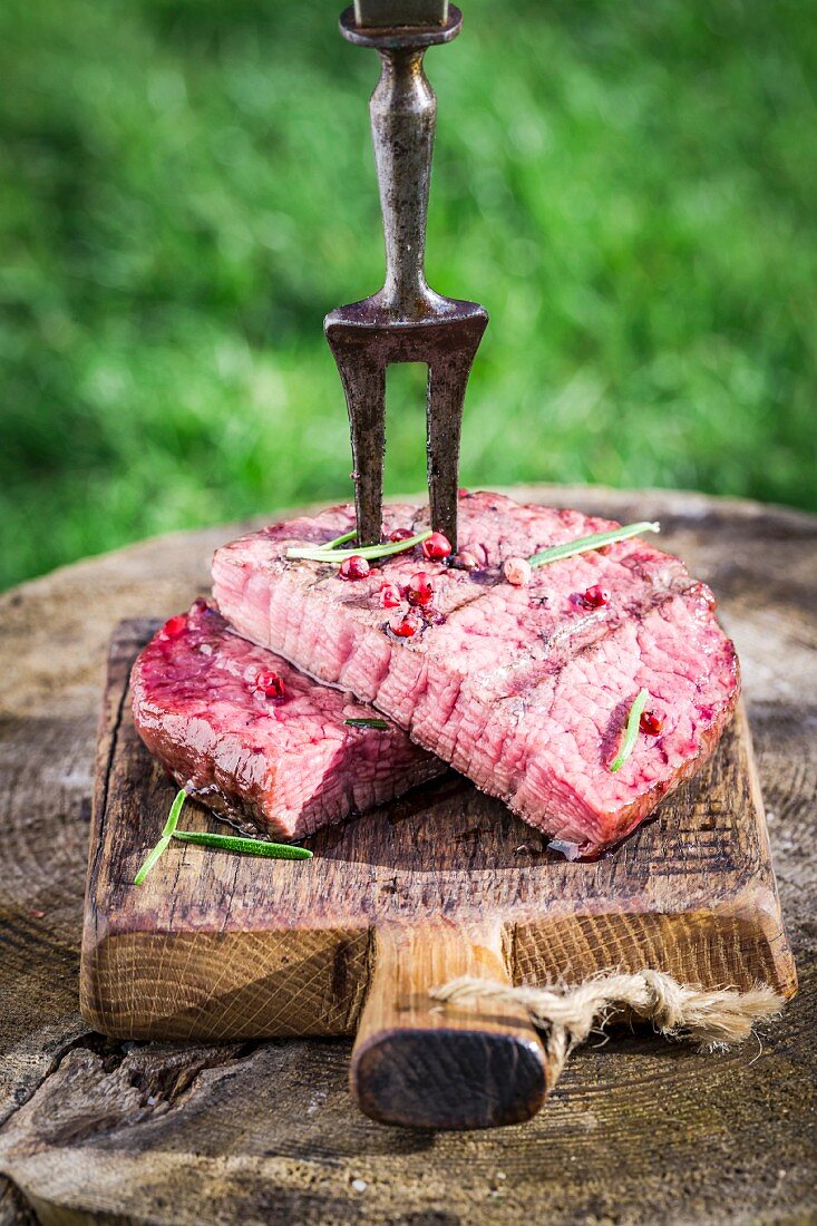 Steak mit Rosmarin und Pfeffer auf Holzbrett