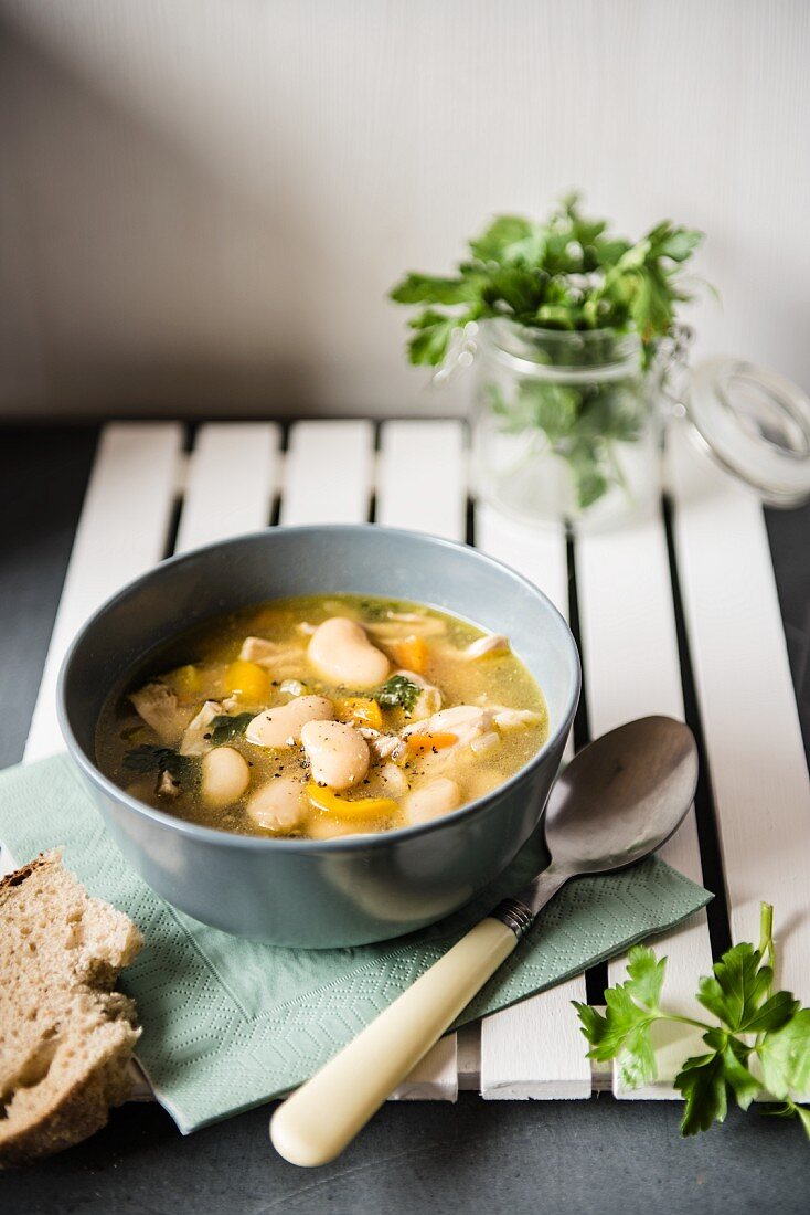 Hühnersuppe mit Butterbohnen, Brot und frischer Petersilie