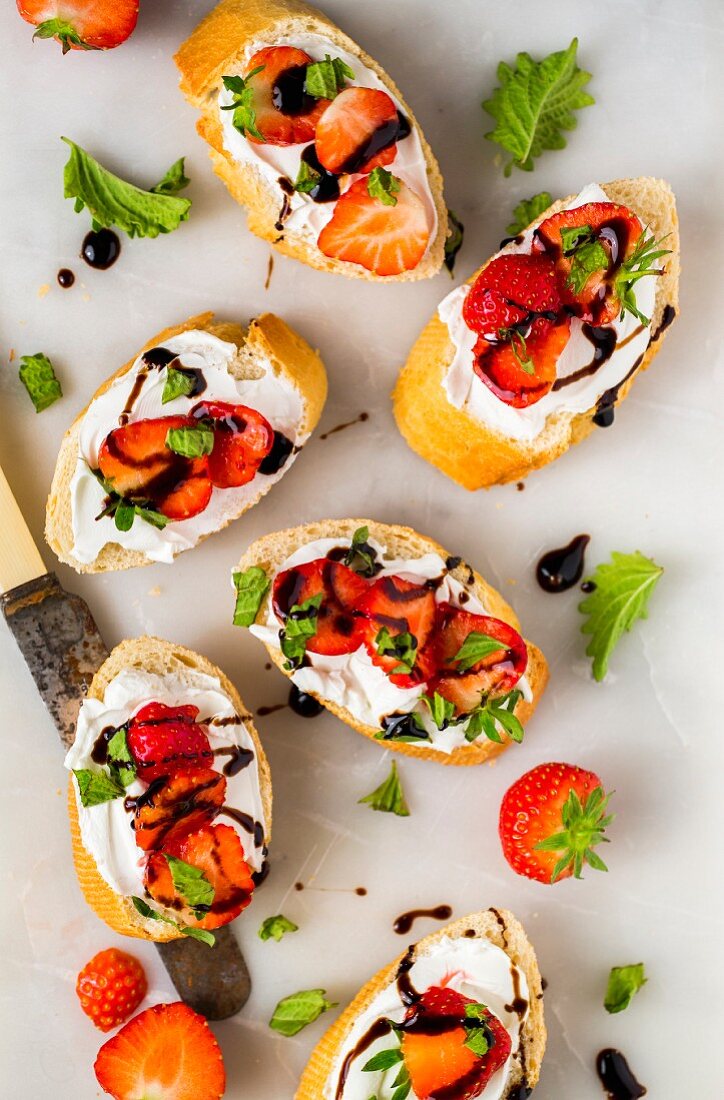 Slices of baguette with strawberries, basil, balsamic vinegar and goats' cheese