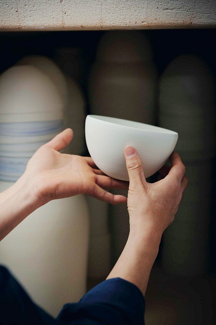 A woman holding a porcelain bowl known as the 'Kap Sun Hwang'