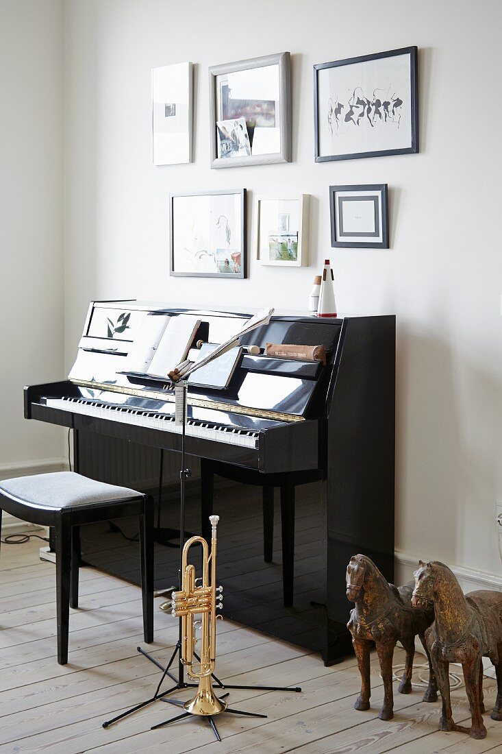 Two horse sculptures and trumpet next to piano