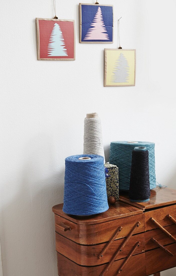 Christmas arrangement of trees hung above reels of thread on vintage sewing box