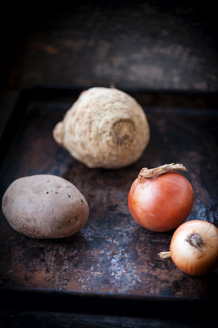 An arrangement of a potato, onions and celeriac