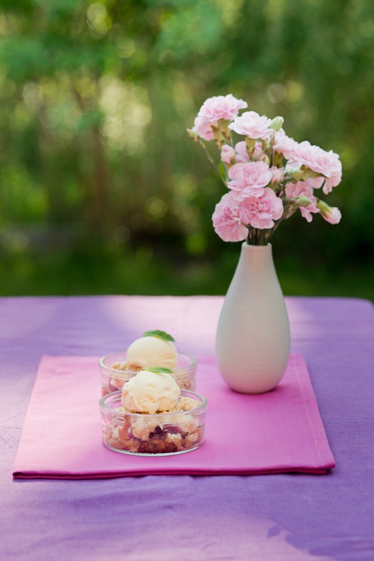 Strawberry crumble with vanilla ice cream in dessert dishes on a garden table