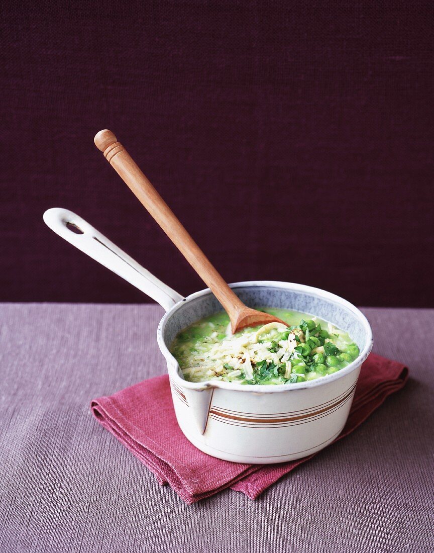 Pea soup in a saucepan with a wooden spoon