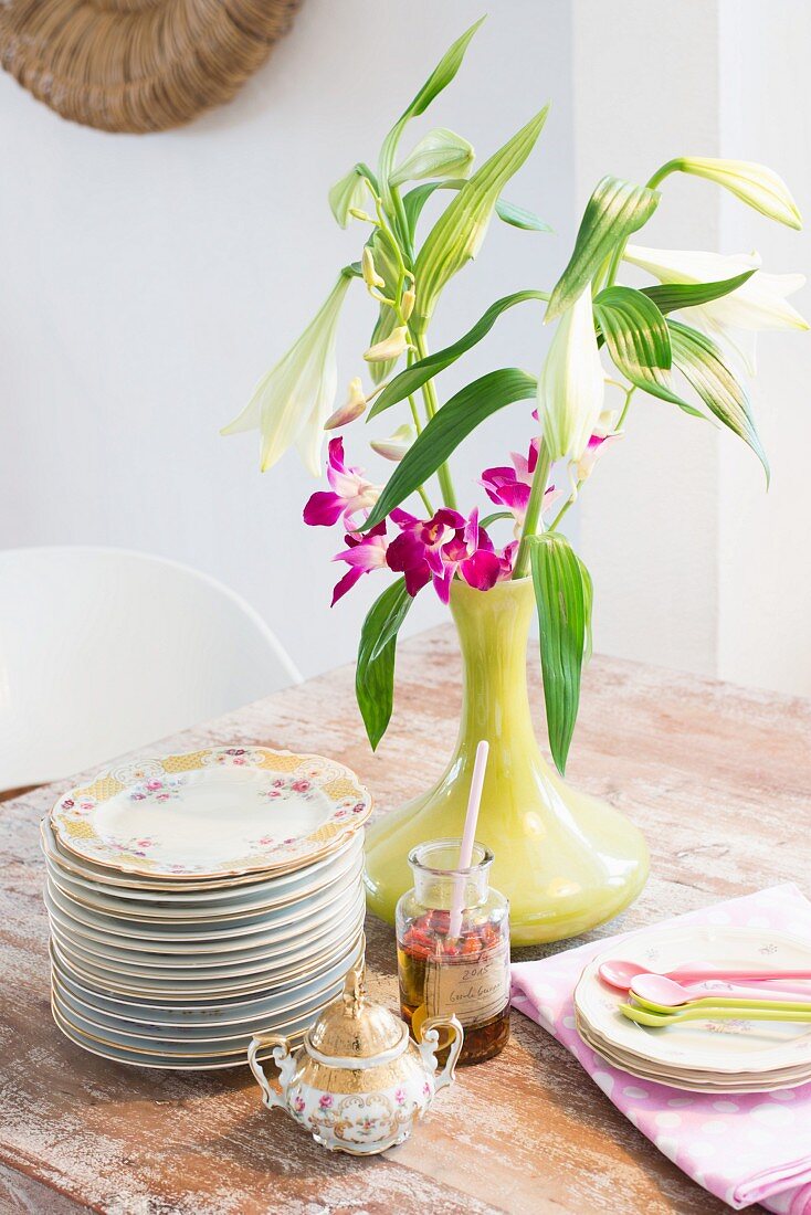 Nostalgisches Geschirr neben moderner grüner Vase mit Blumen