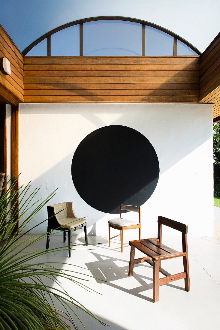 Various chairs on veranda with black circle on wall
