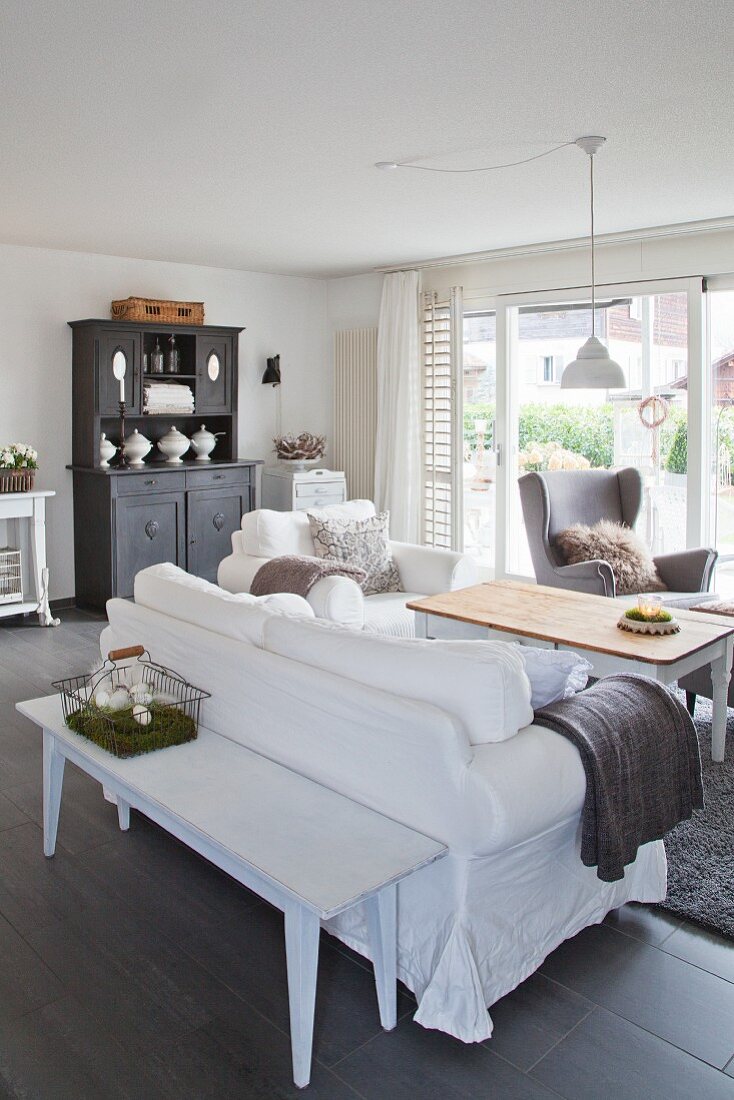 Old wooden bench behind sofa in grey and white living room