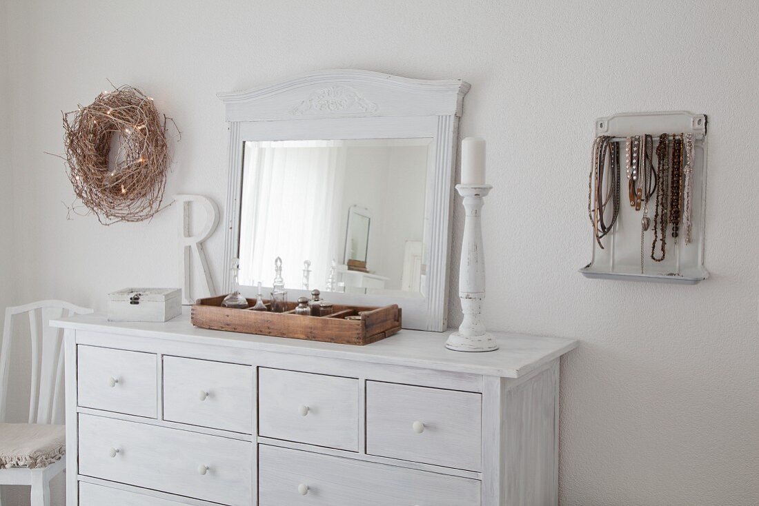 Old mirror on white-painted chest of drawers