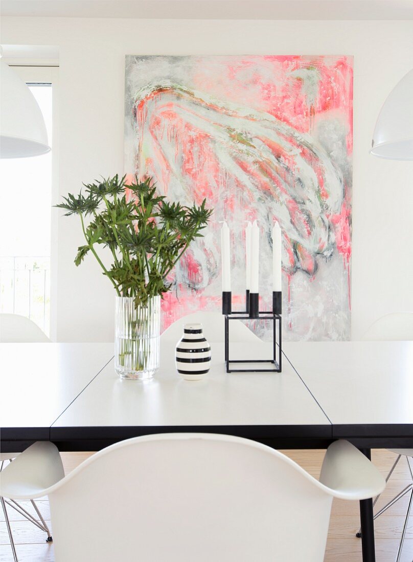 Vase and candelabra on dining table in front of abstract painting