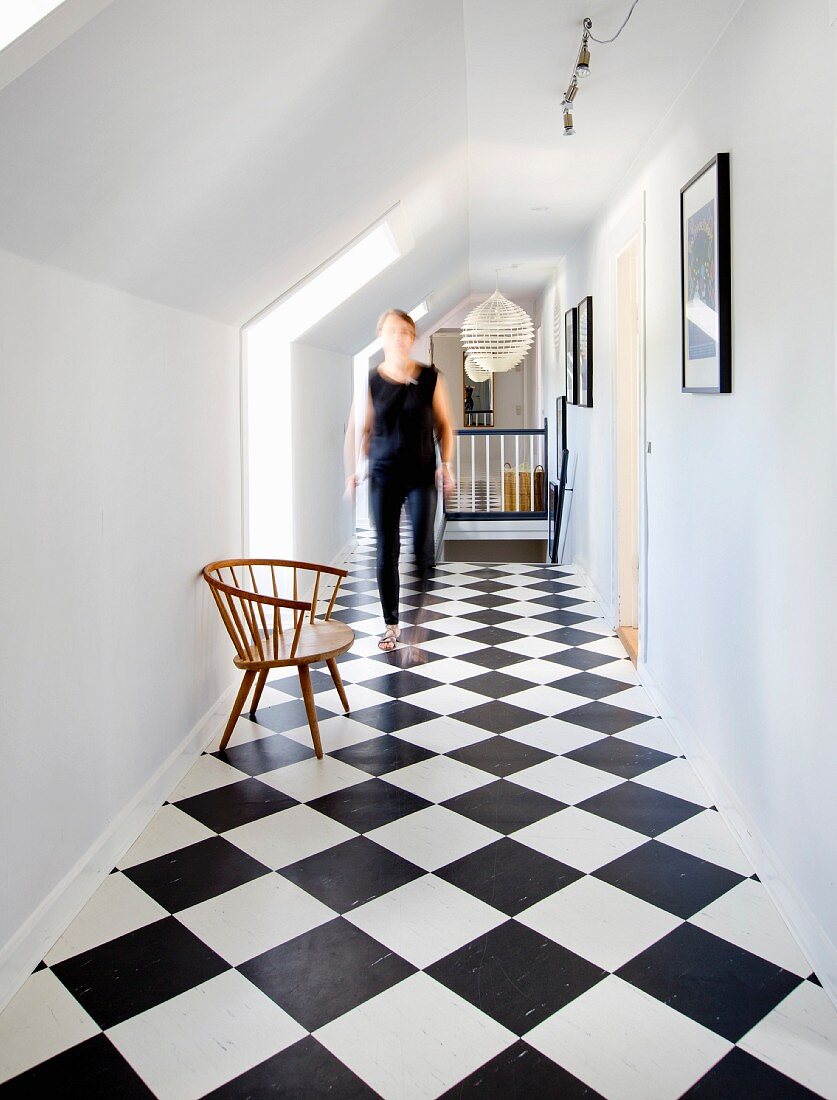 Black and white chequered floor in attic corridor with woman in background