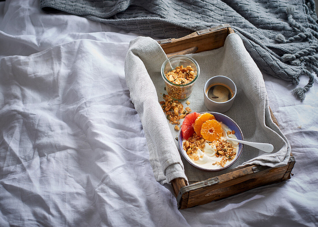 Müsli mit Joghurt, Zitrusfrüchten und Nüssen auf Tablett