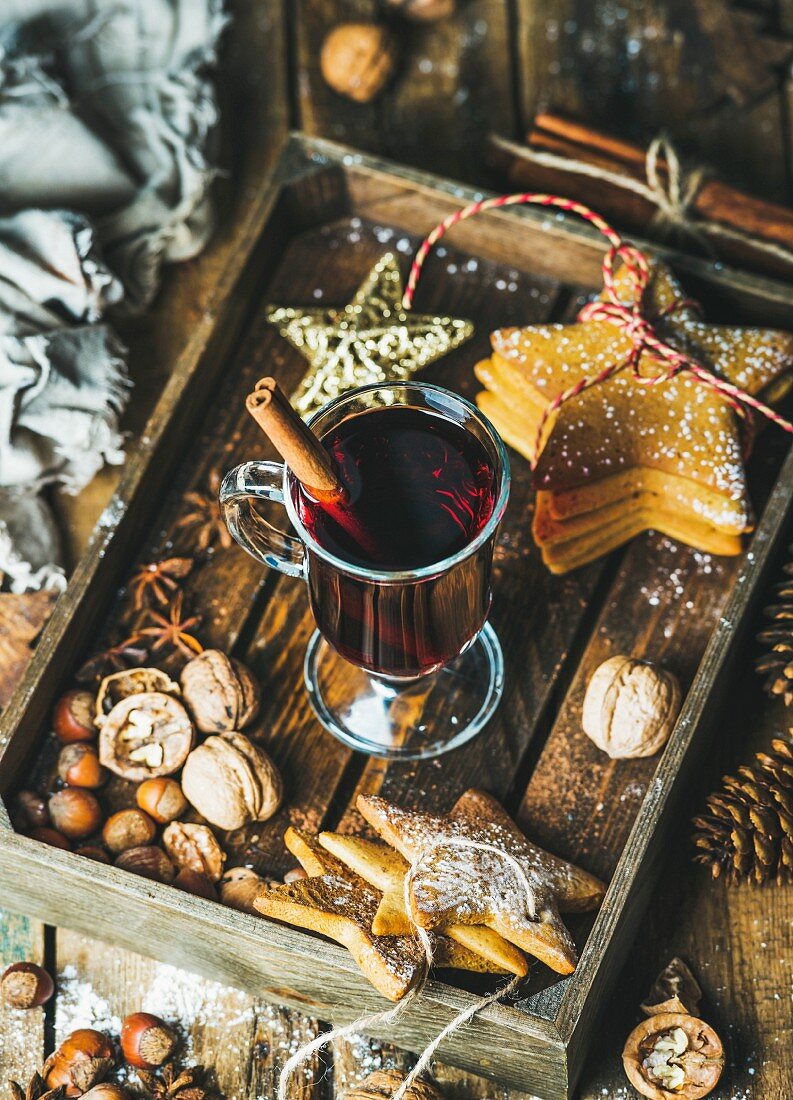 Glass of mulled wine, Christmas decoration toys, gingerbread cookies, nuts, cinnamon, anise and pine cones