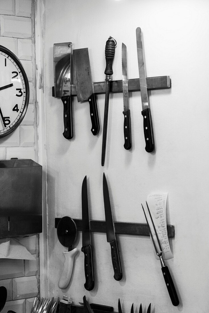 Assorted knives and kitchen utensils on magnetic racks in the kitchen