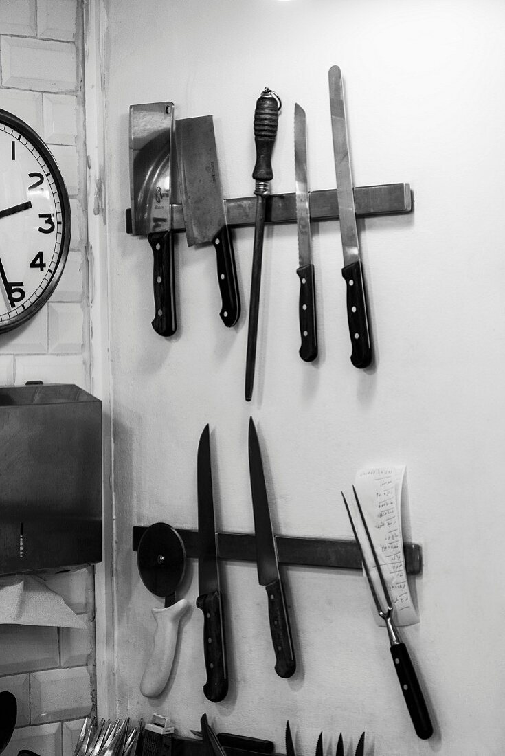 Verschiedene Messer und Küchenutensilien an Magnetleisten in Küche