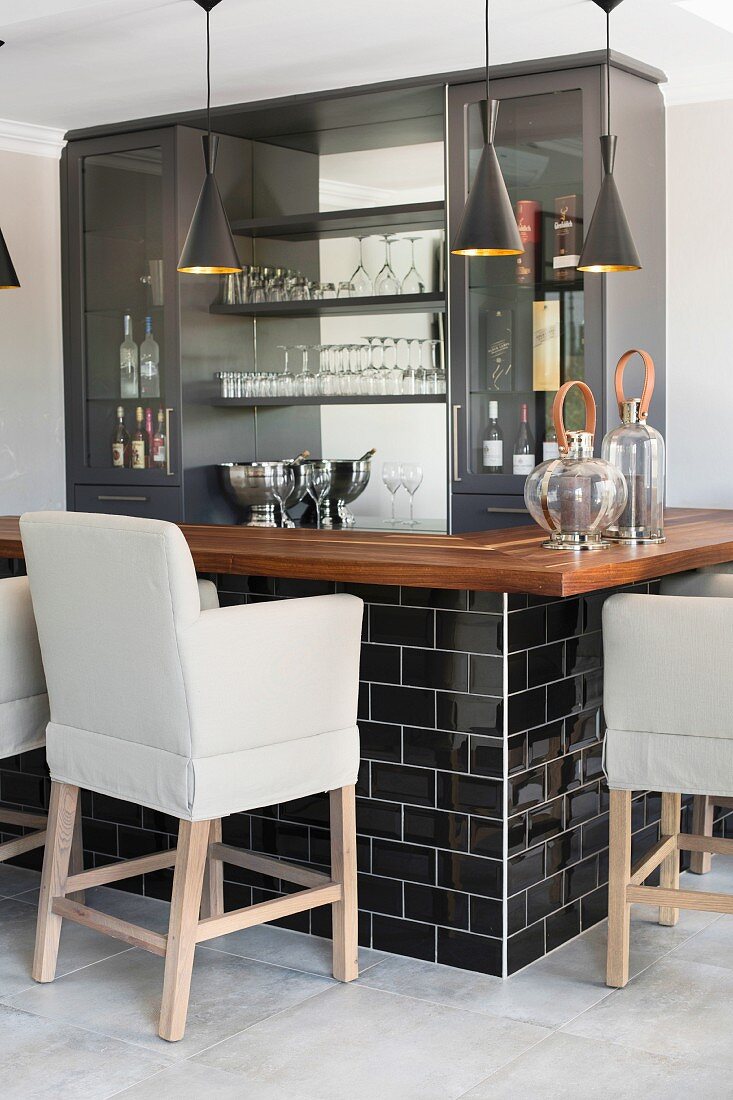 Upholstered bar stools at black and grey bar with wooden worksurface