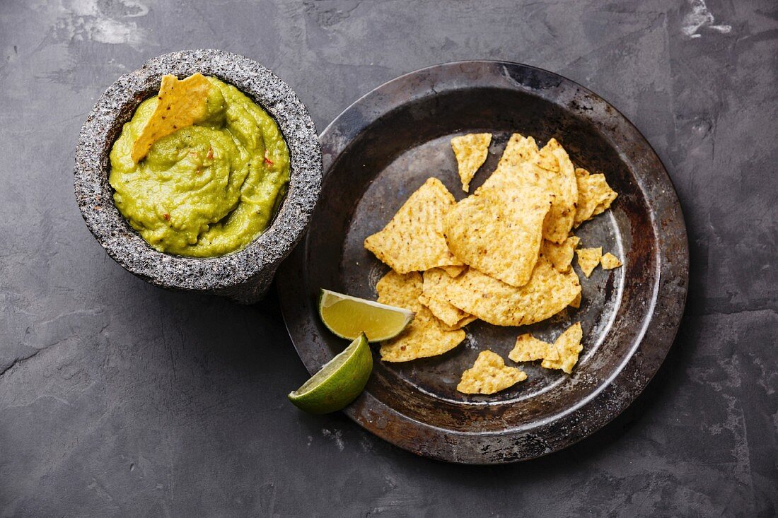 Guacamole with nachos on a grey concrete surface