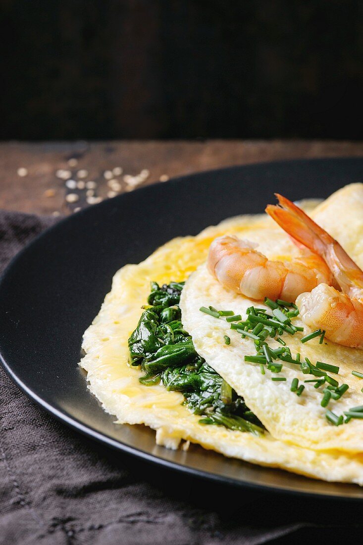 Omelet with cooked spinach and fried shrimps prawns, served with cutting chive and sesame seeds