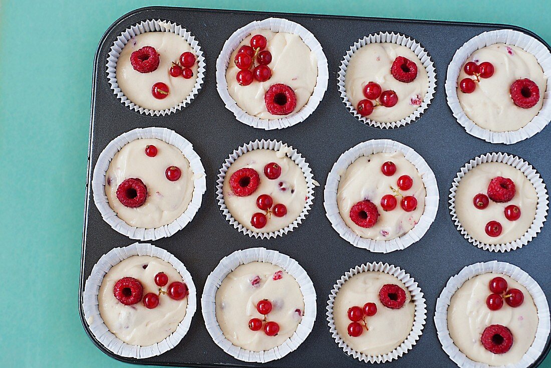 Cream cheese muffins with red berries before baking