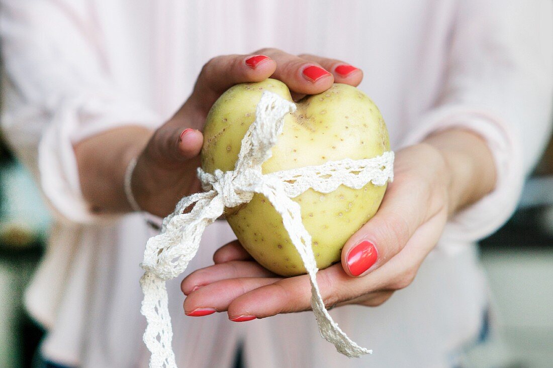 Frauenhände halten Kartoffelherz