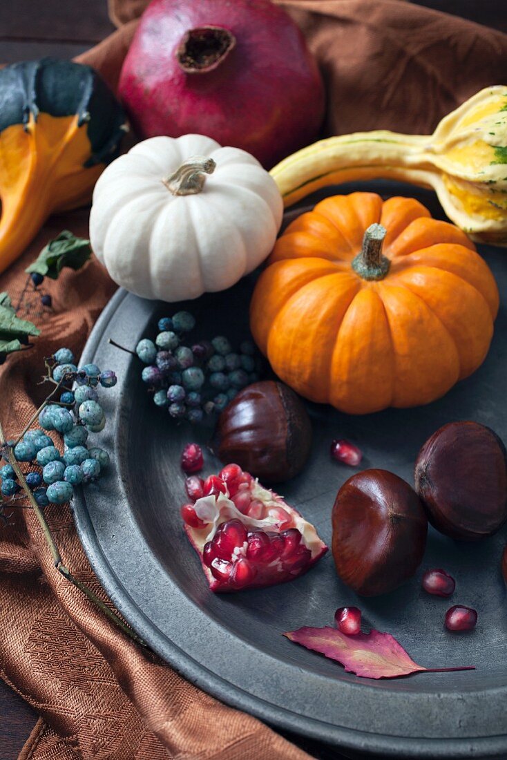 An autumnal arrangement of pumpkins, chestnuts, pomegranates and berries