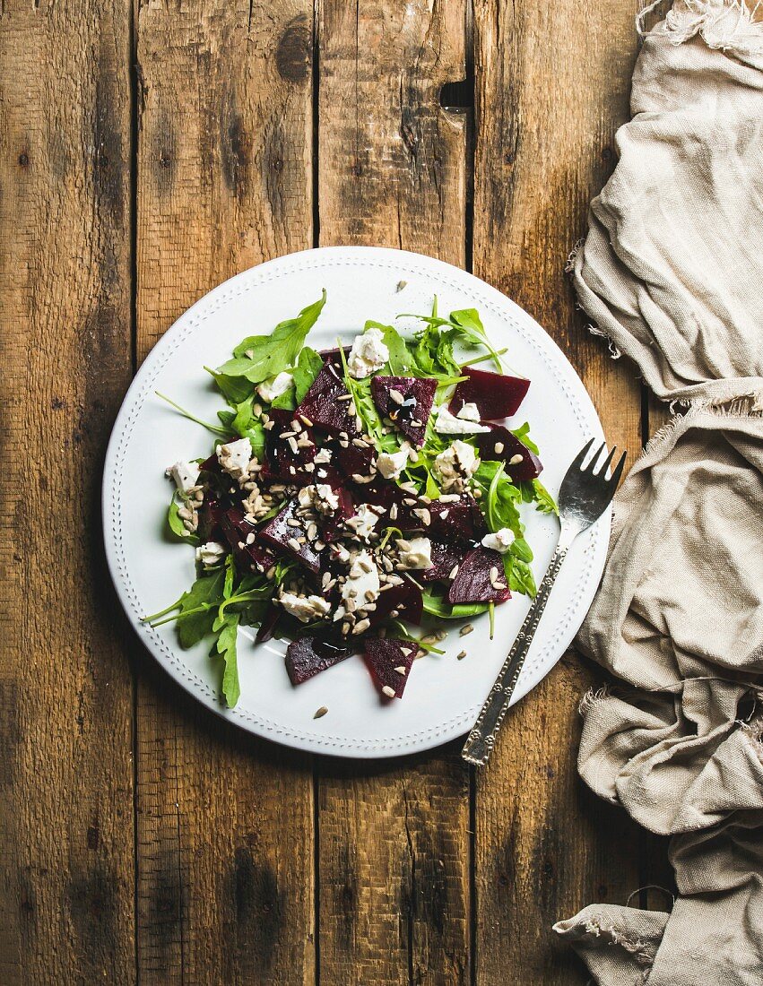 Arugula, beetroot, feta cheese and sunflower seed salad in white ceramic plate