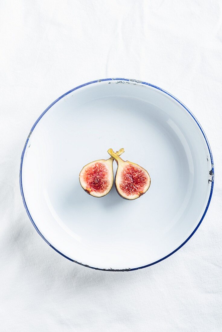 A fig cut in half on an enamel plate