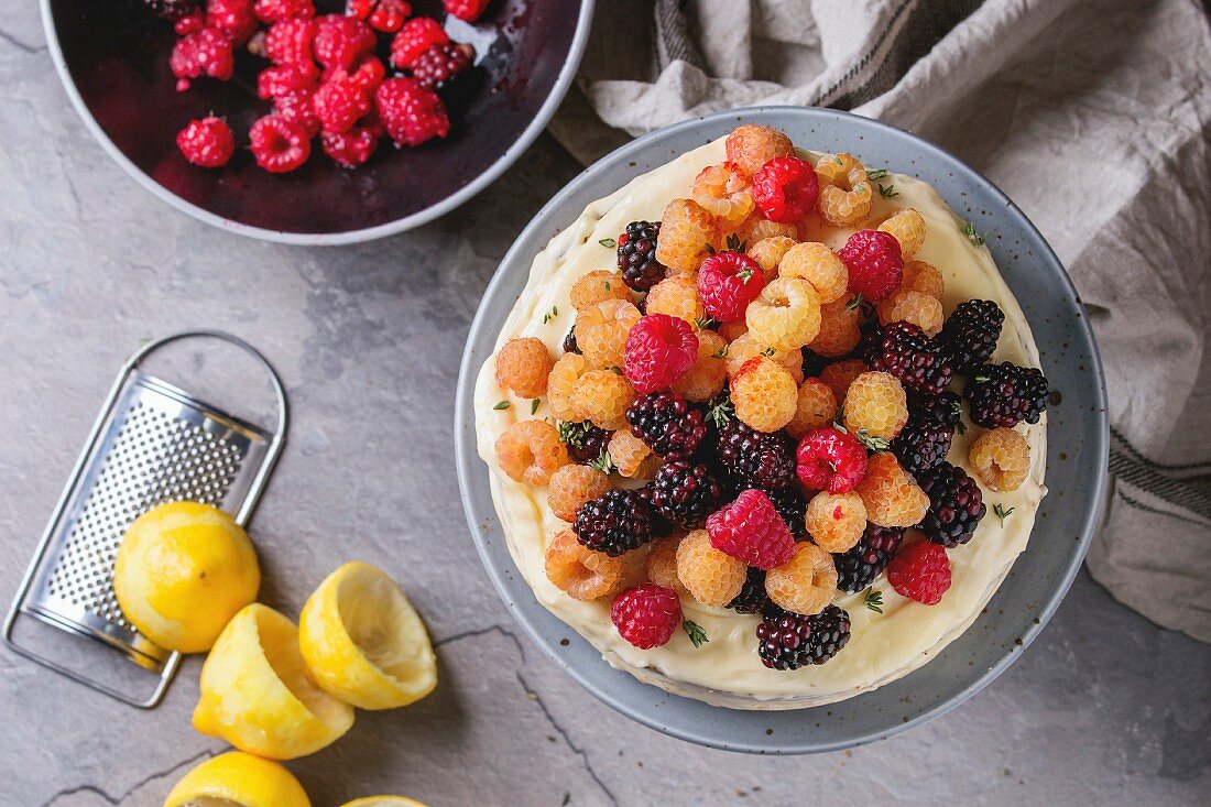 Sponge cake with lemon cream, decorated by fresh colorful yellow red raspberries and dewberries