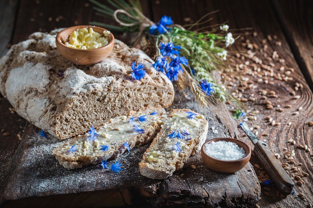 Homemade wholemeal bread with butter and salt on an old wooden board