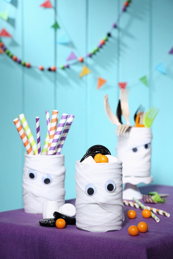 Hand-crafted mummy tins decorating table for Halloween
