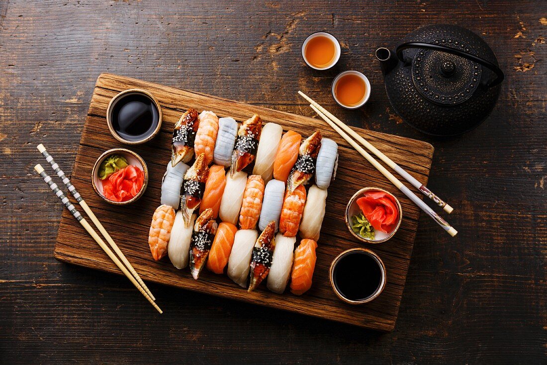 Nigiri-Sushi mit Essstäbchen für Zwei auf Holzbrett und grüner Tee