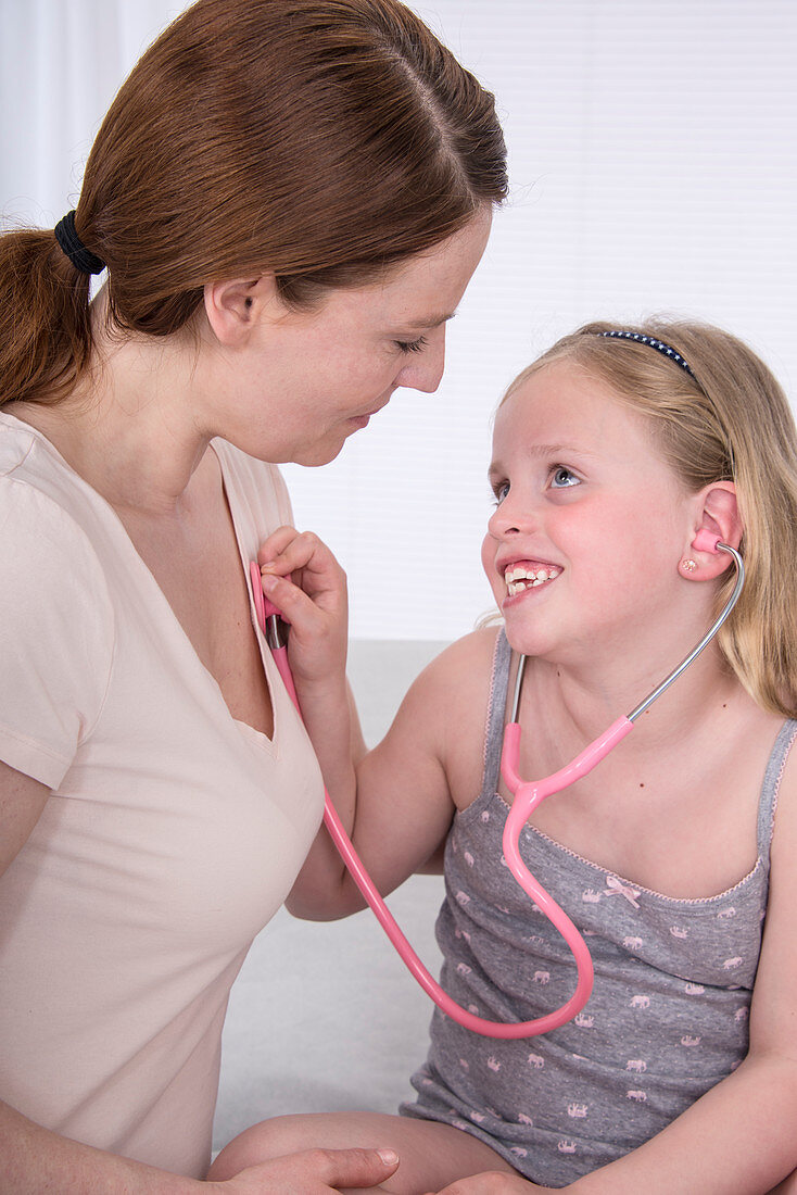Girl using stethoscope with mother