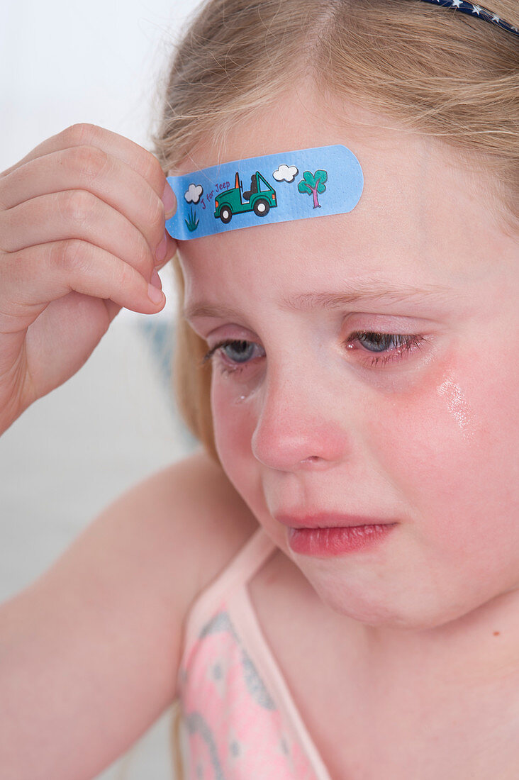Girl with plaster on forehead,crying
