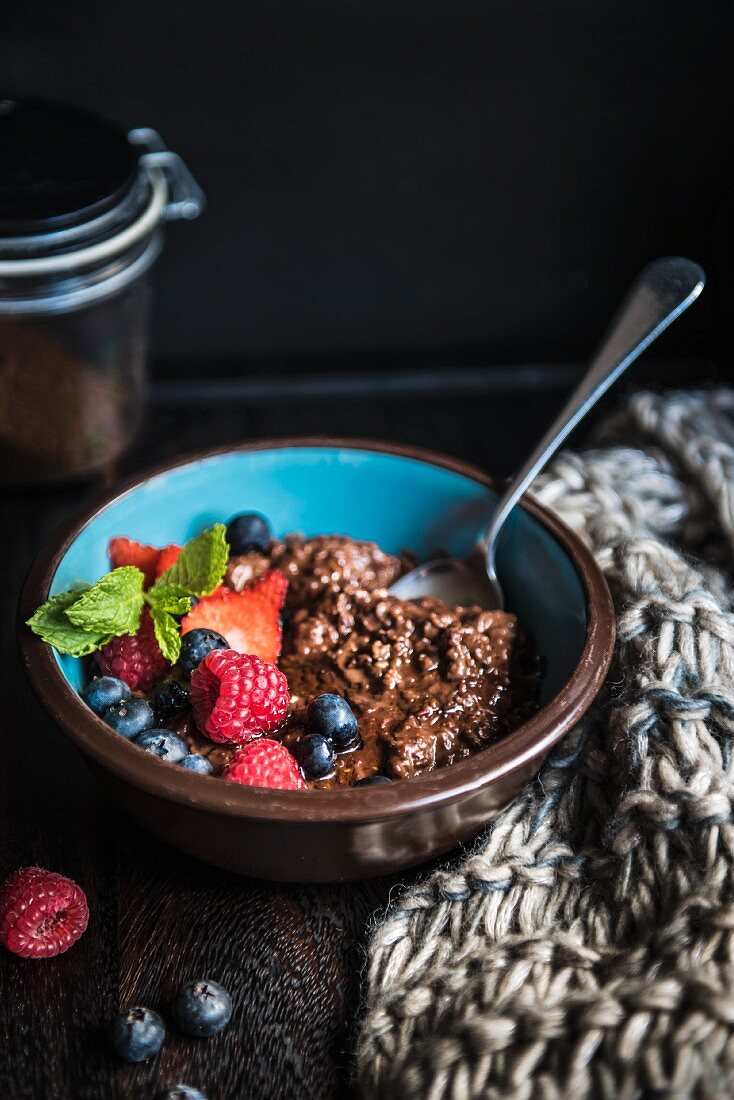 A bowl of chocolate porridge with berries and honey