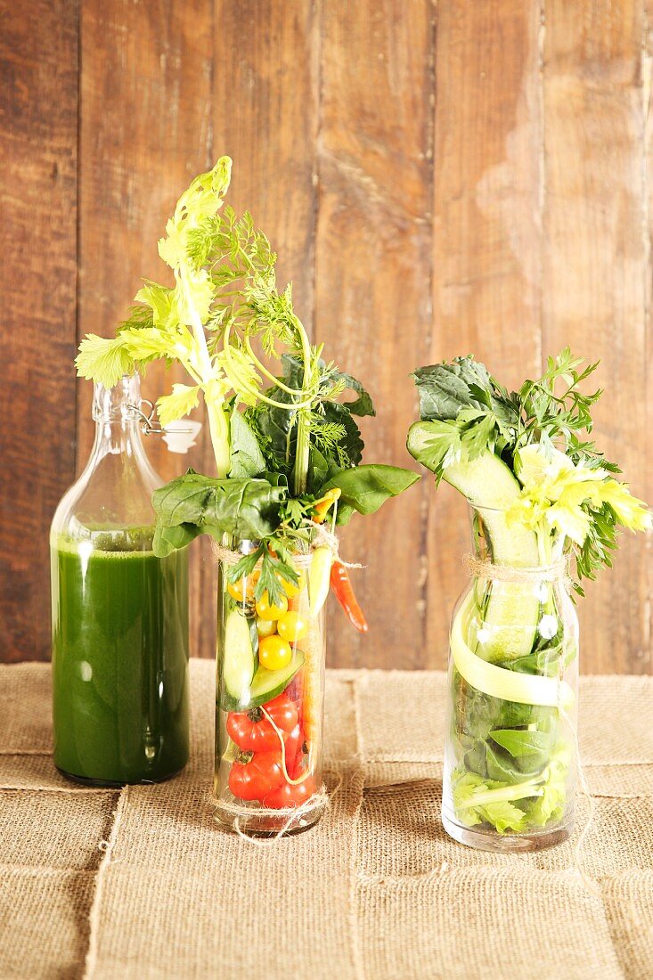 Healthy mixed vegetable juice with ingredients in glasses and a bottle