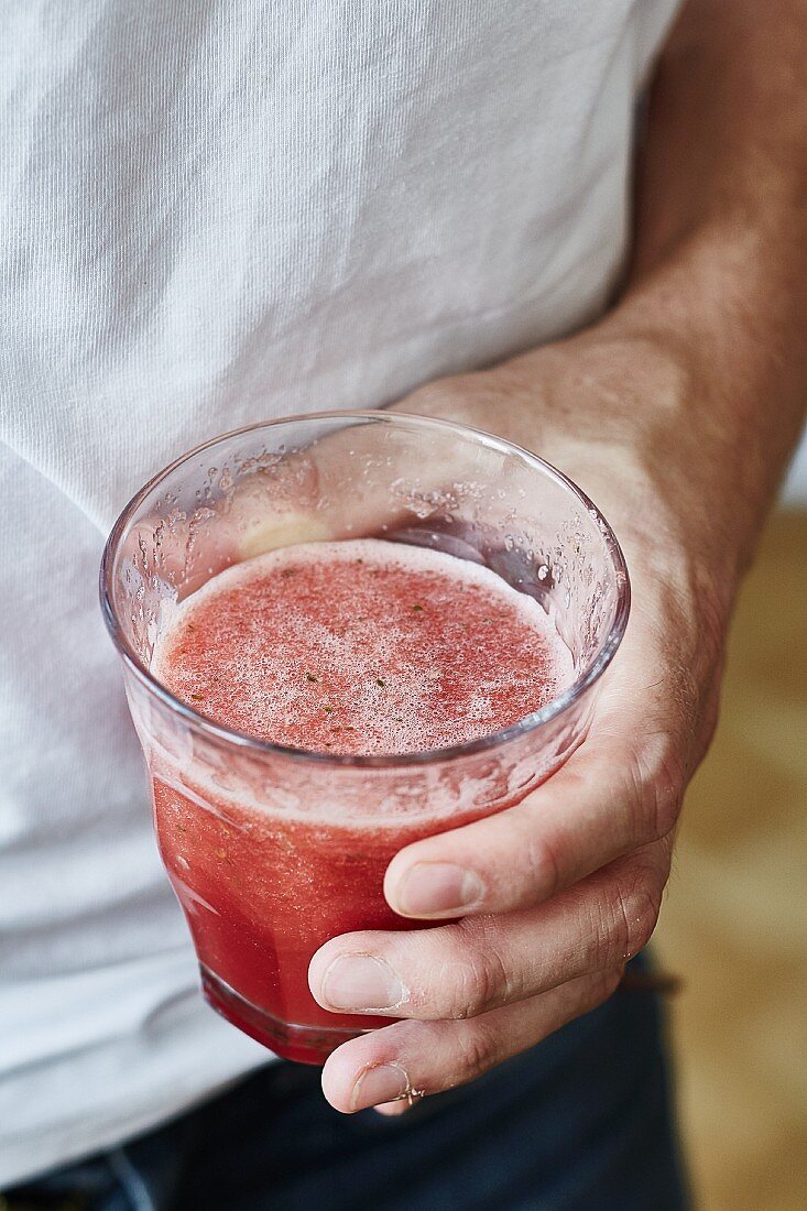 Mann hält ein Glas Wassermelonen-Smoothie