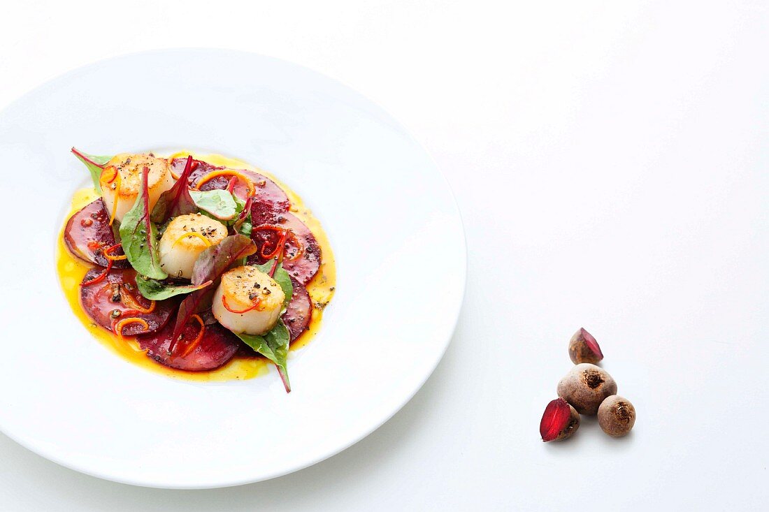 Scallops on a bed of beetroot carpaccio with spiced orange butter