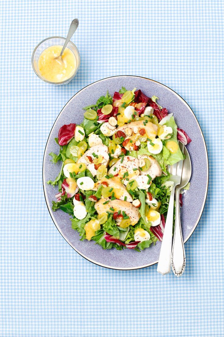 A salad with grilled chicken, grapes, mozzarella and apricot dressing