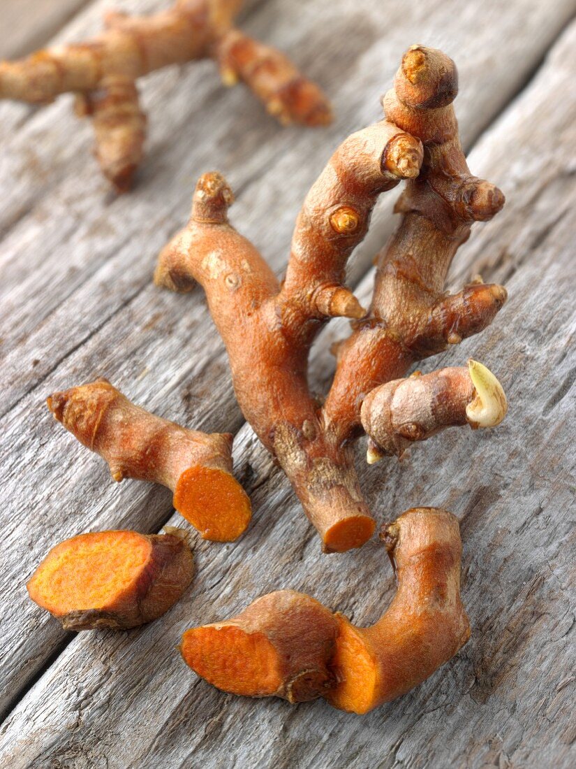 Fresh turmeric roots (Curcuma longa) on a wooden surface