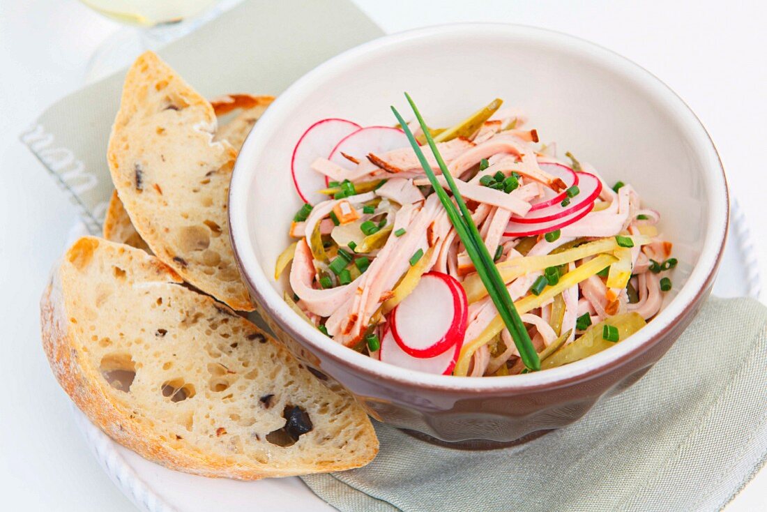Sausage salad with cheese and radish served with olive bread