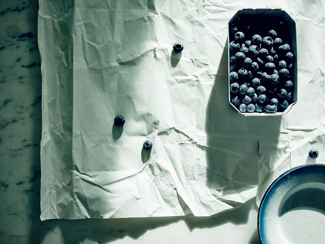 Blueberries in a cardboard punnet on paper