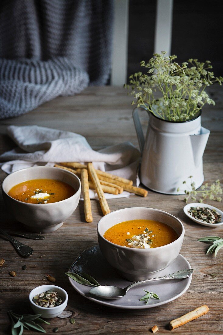 Creamy pumpkin soup in bowls on a rustic wooden table
