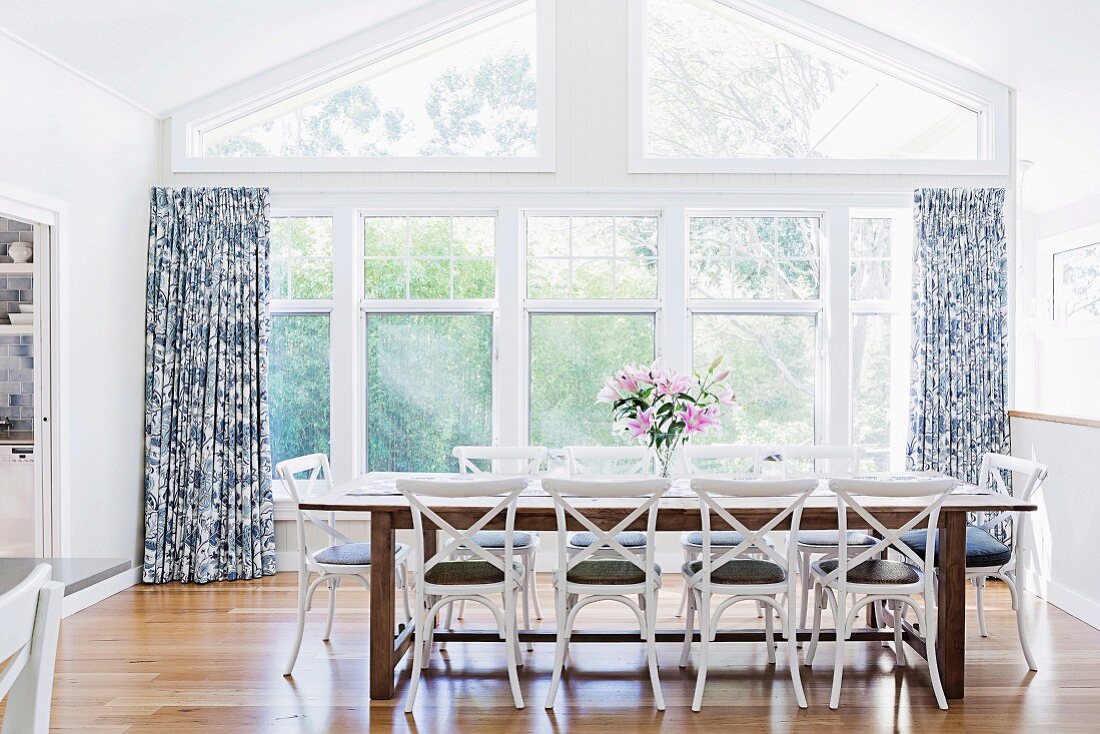 Long dining table with country-style chairs in front of a window