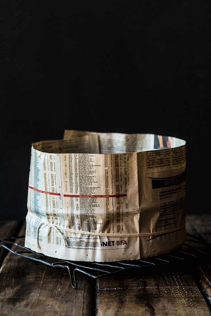A baking tin wrapped in newspaper for a spelt and amaretto fruit cake