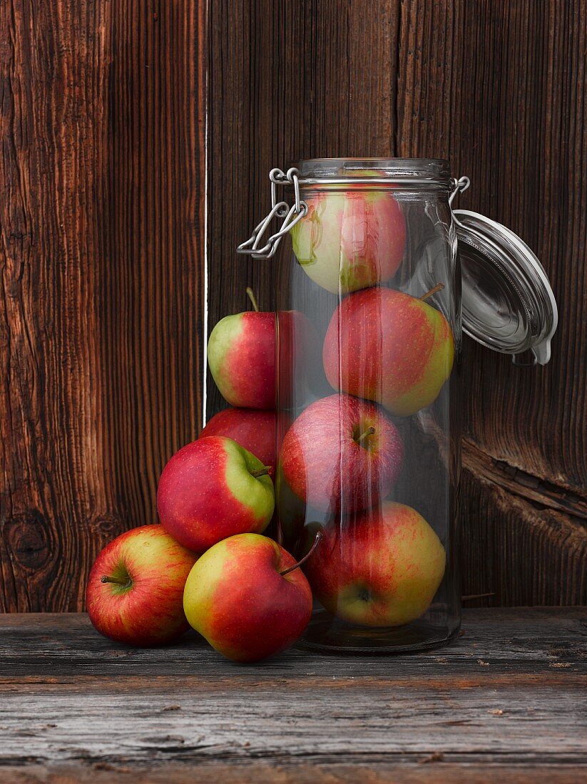 Fresh apples inside and next to a glass storage jar