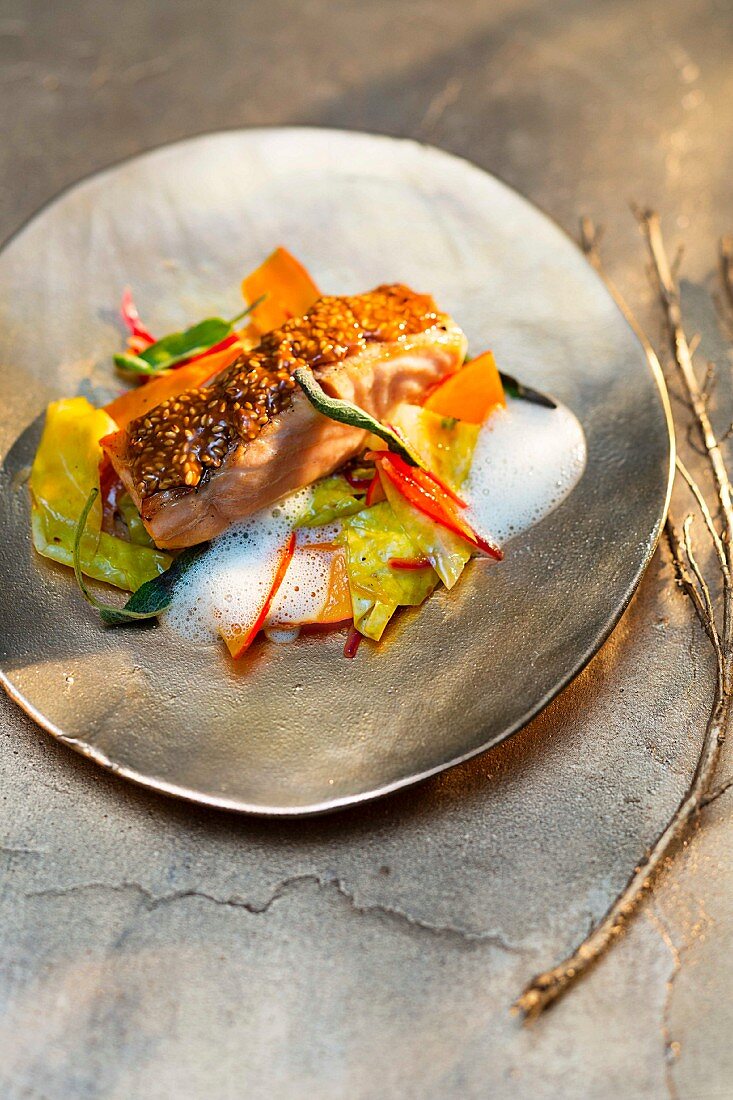 Salmon fillet with a sesame crust on a bed of vegetables